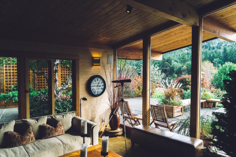 A cozy wood paneled living room opening onto a garden view