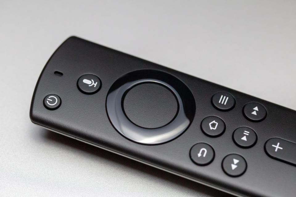 A black remote control on a light gray surface