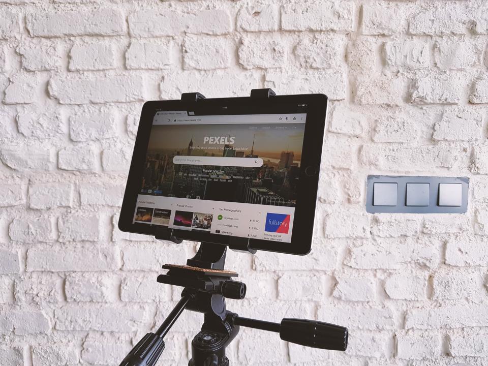 A tablet on a tripod showing a website against a brick wall