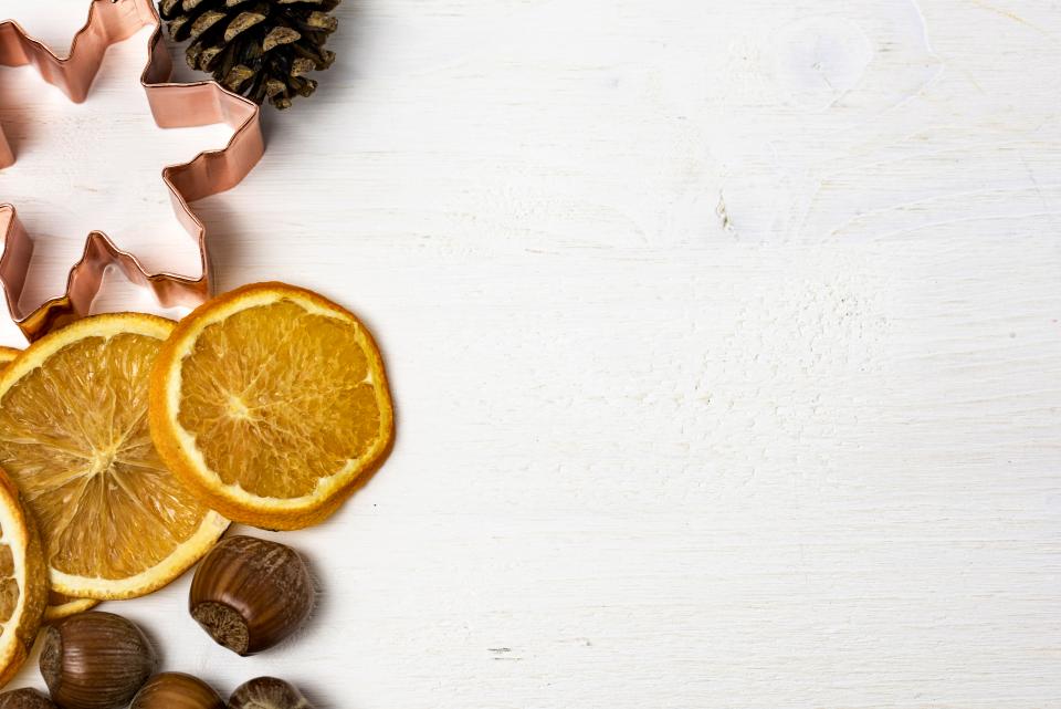 Dried orange slices and a pinecone on a white wooden table
