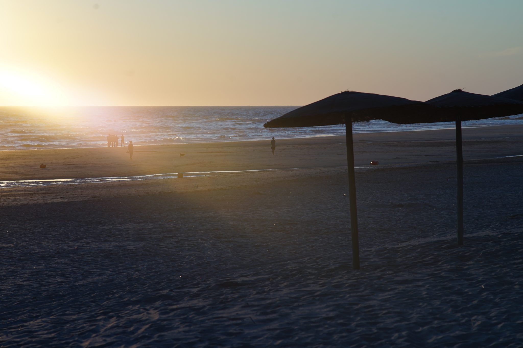 Beach umbrellas silhouetted against a warm summer sunset