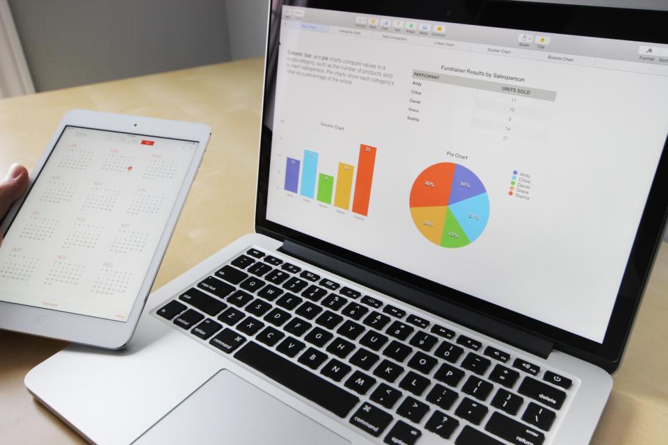 Calendar app open on a tablet next to a laptop showing charts