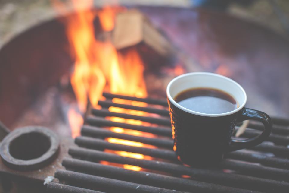 A mug of coffee resting on a fire pit grill