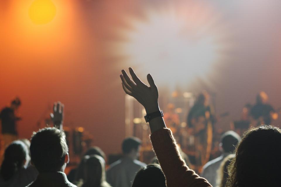 A raised hand silhouetted against concert stage lights
