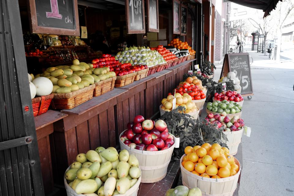 A fruit and vegetable market stall on a city sidewalk