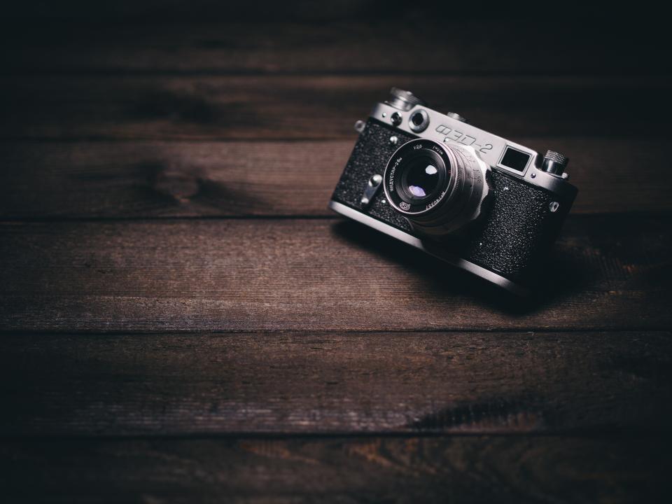 A vintage camera resting on a dark wooden surface